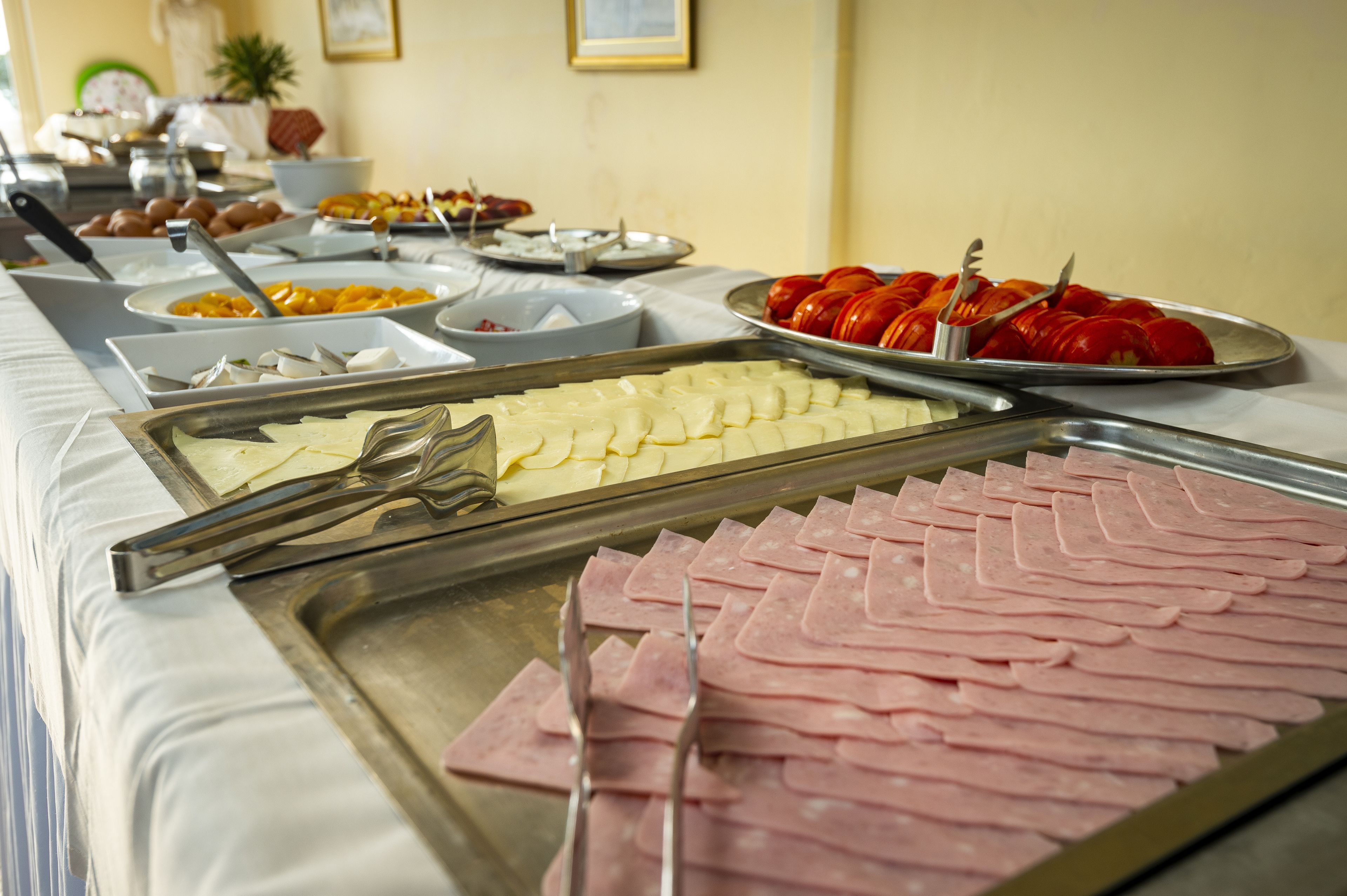 Un bufé con distintos alimentos, como jamón en rodajas, queso y tomates.