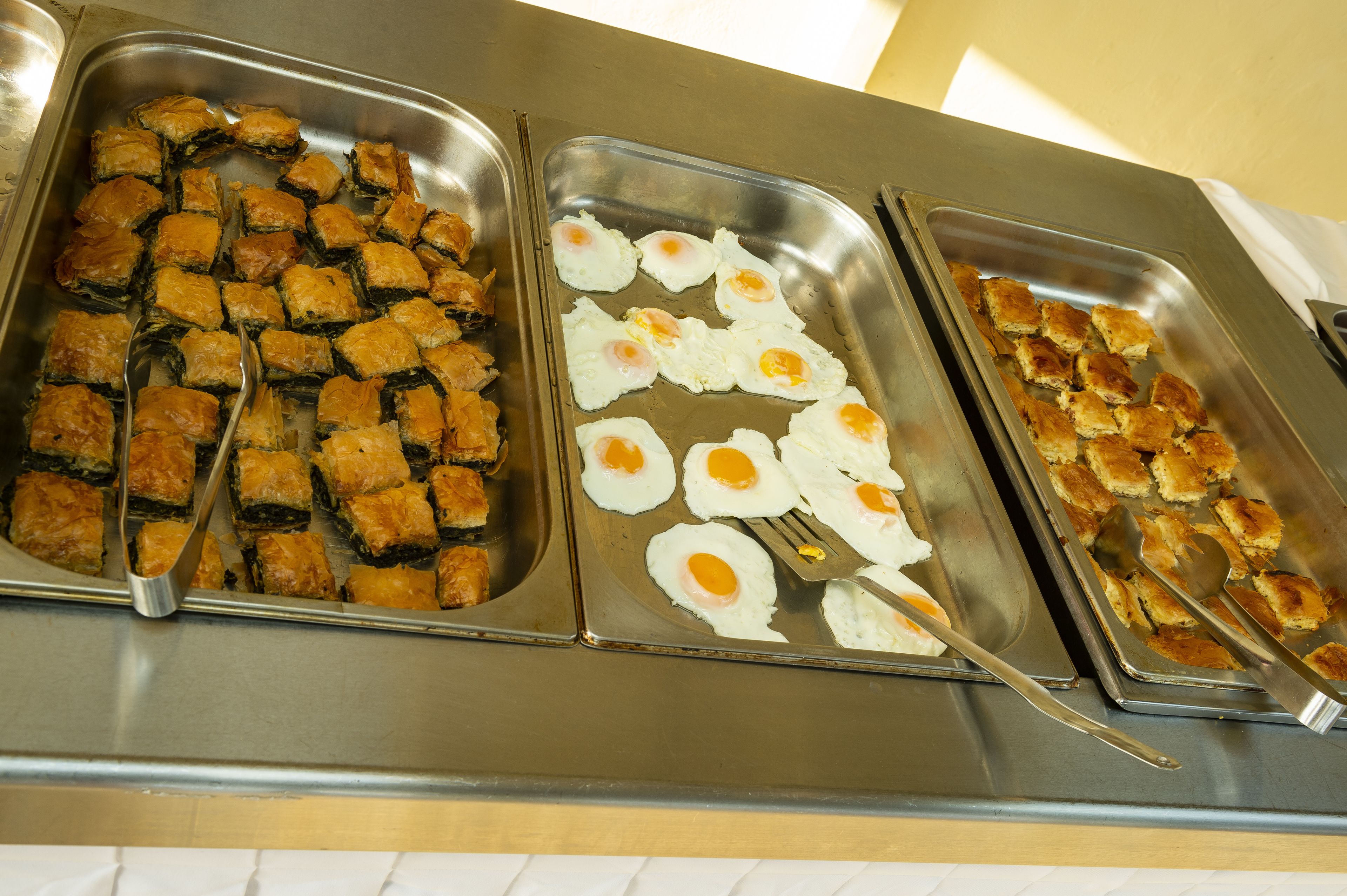 Een buffet met schalen vol gebak en gebakken eieren.