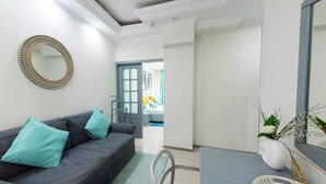 A modern living room with a grey sofa, teal cushions, a round mirror, and a white vase with plants. - Relax Comfort Suites (Bucharest)