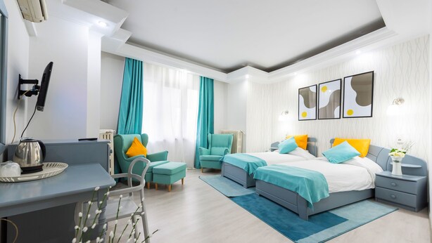 A modern hotel room with a desk, two beds, a chair, and a nightstand. - Relax Comfort Suites (Bucharest)