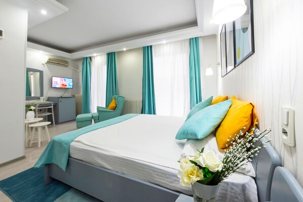 A modern hotel room with a large bed, a desk, and a TV.
