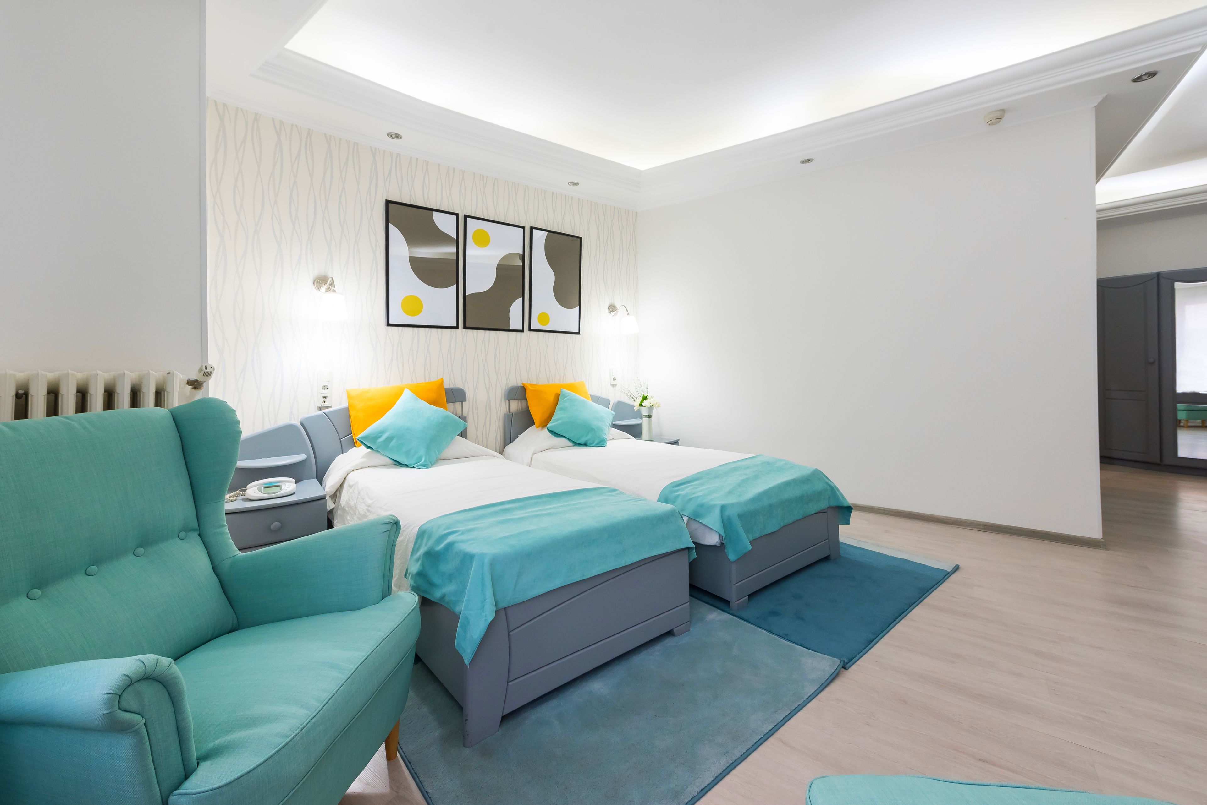 A modern hotel room with two beds, a sofa, and a small table.
