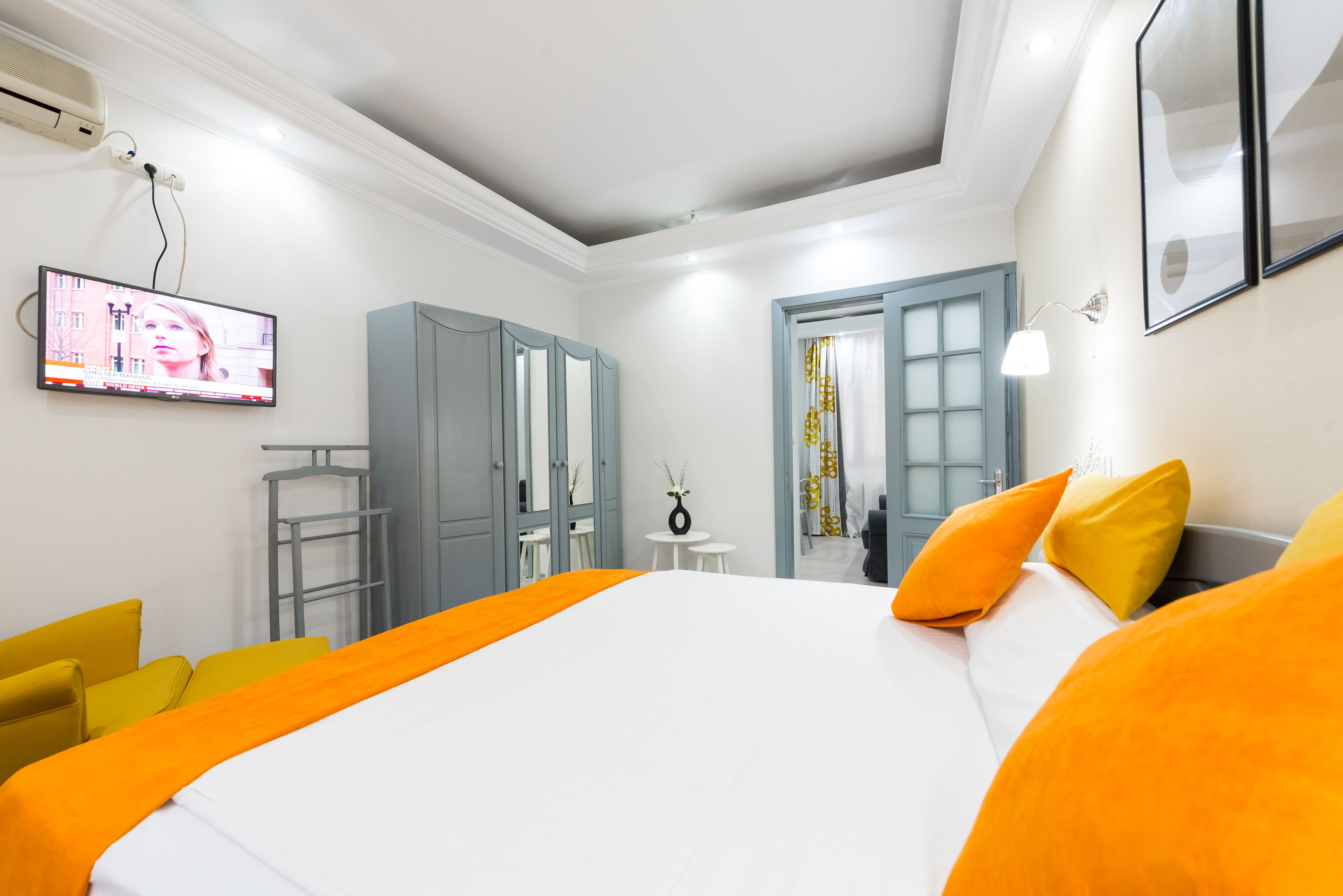 A modern hotel room with a large bed, a TV mounted on the wall, and a desk with a chair.