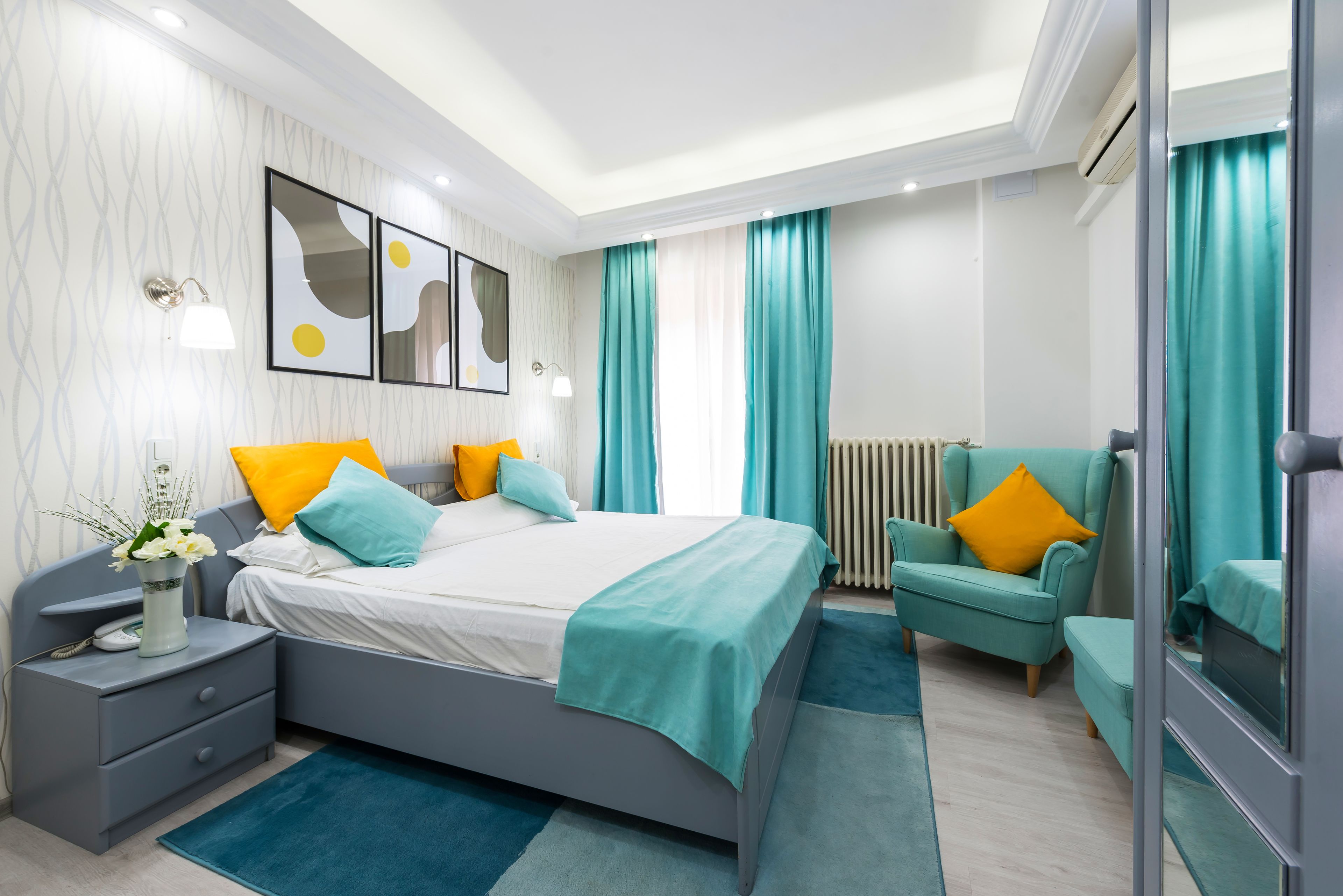 Un dormitorio moderno con cama, mesita de noche, silla y obra de arte en la pared.