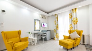 A modern living room with two yellow armchairs, a small white table, and a TV mounted on the wall. - Relax Comfort Suites (Bucharest)