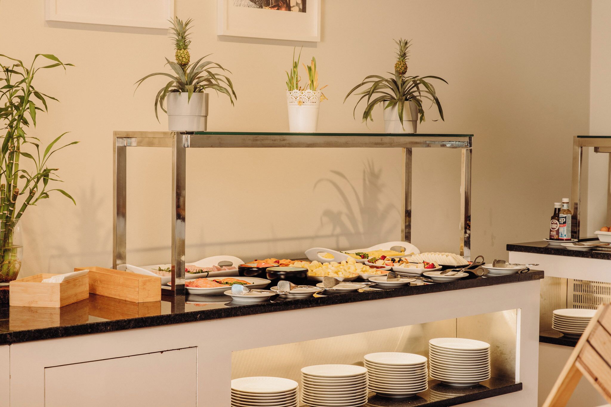 Un buffet proposant une variété de plats, une vitrine réfrigérée et des plantes en pot.