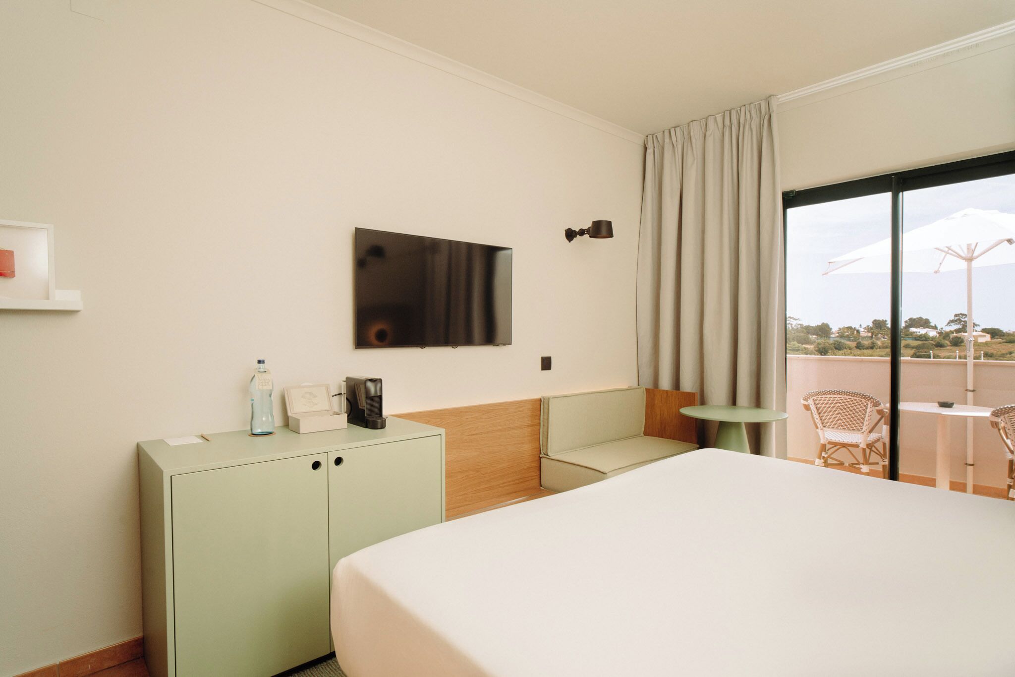Una camera d'albergo con un letto, una scrivania, una sedia, una televisione e vista sull'esterno.