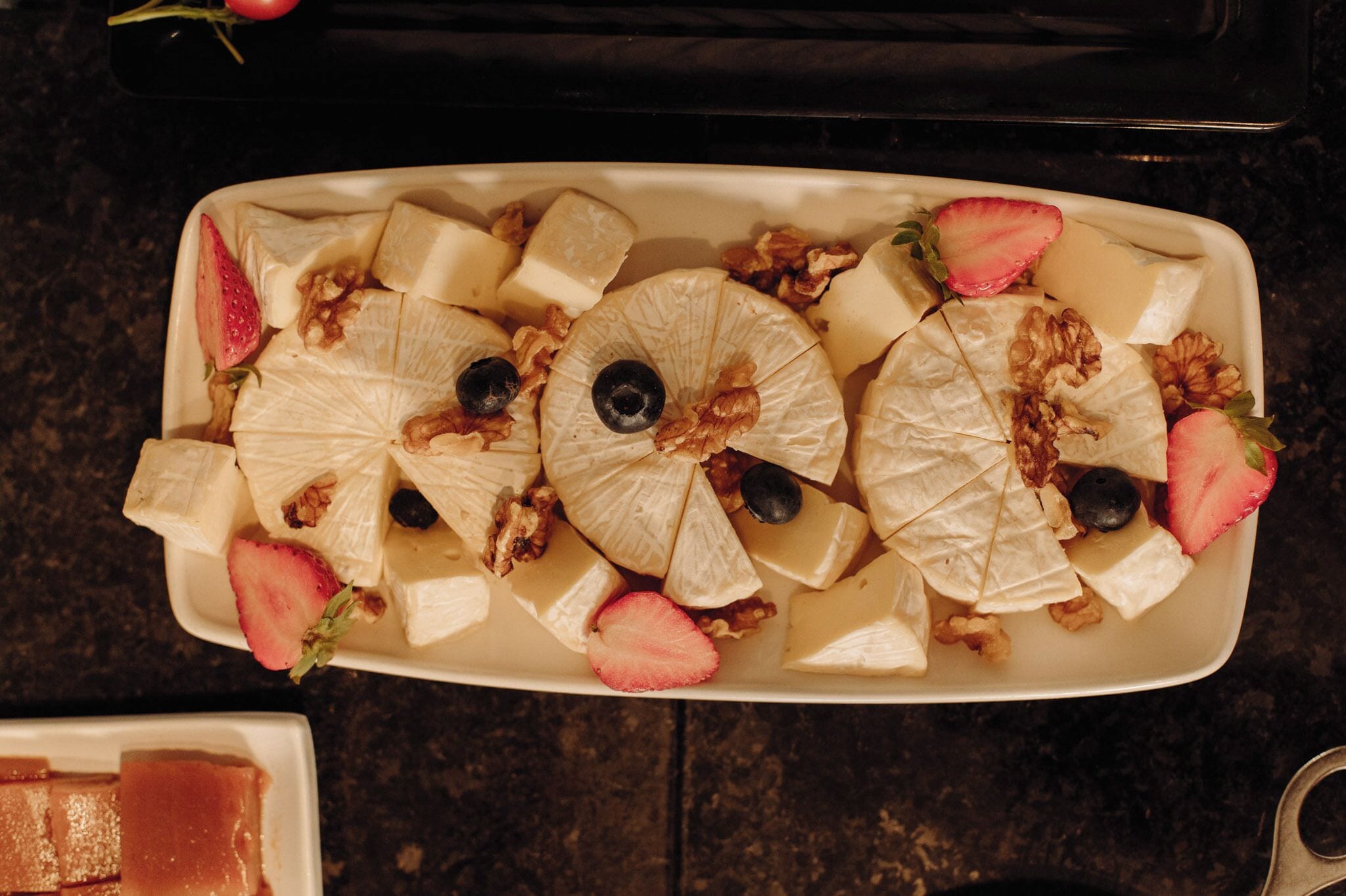 A rectangular white plate with sliced fruits and nuts.