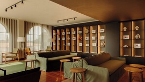 A modern living room with a sofa, chairs, a lamp, and a wall with framed pictures and decorative items.