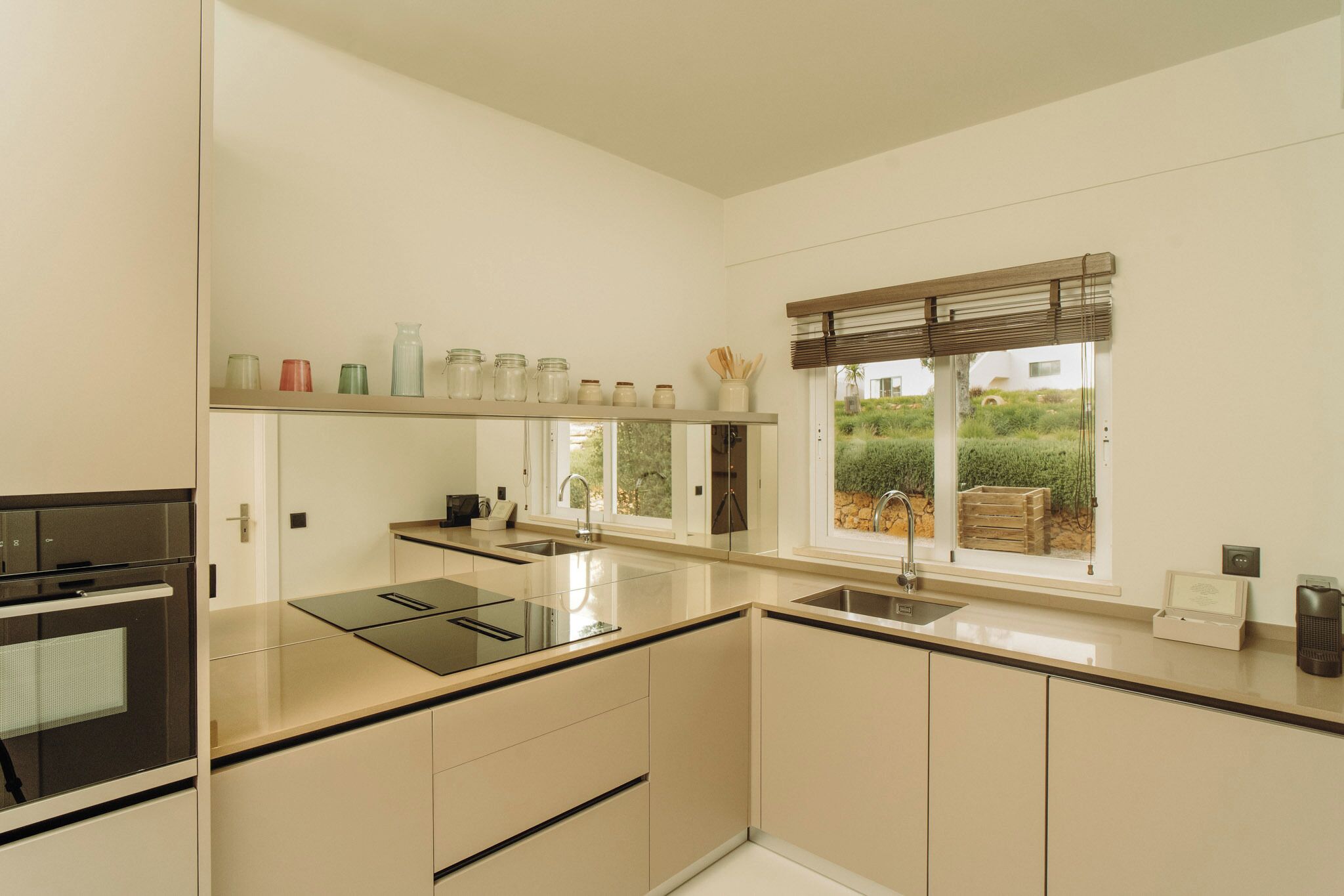 Una cocina moderna con una isla central, horno empotrado y ventana con vistas a la vegetación.