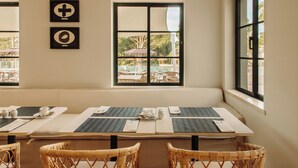 Un área de comedor con un banco, mesas y sillas de mimbre.