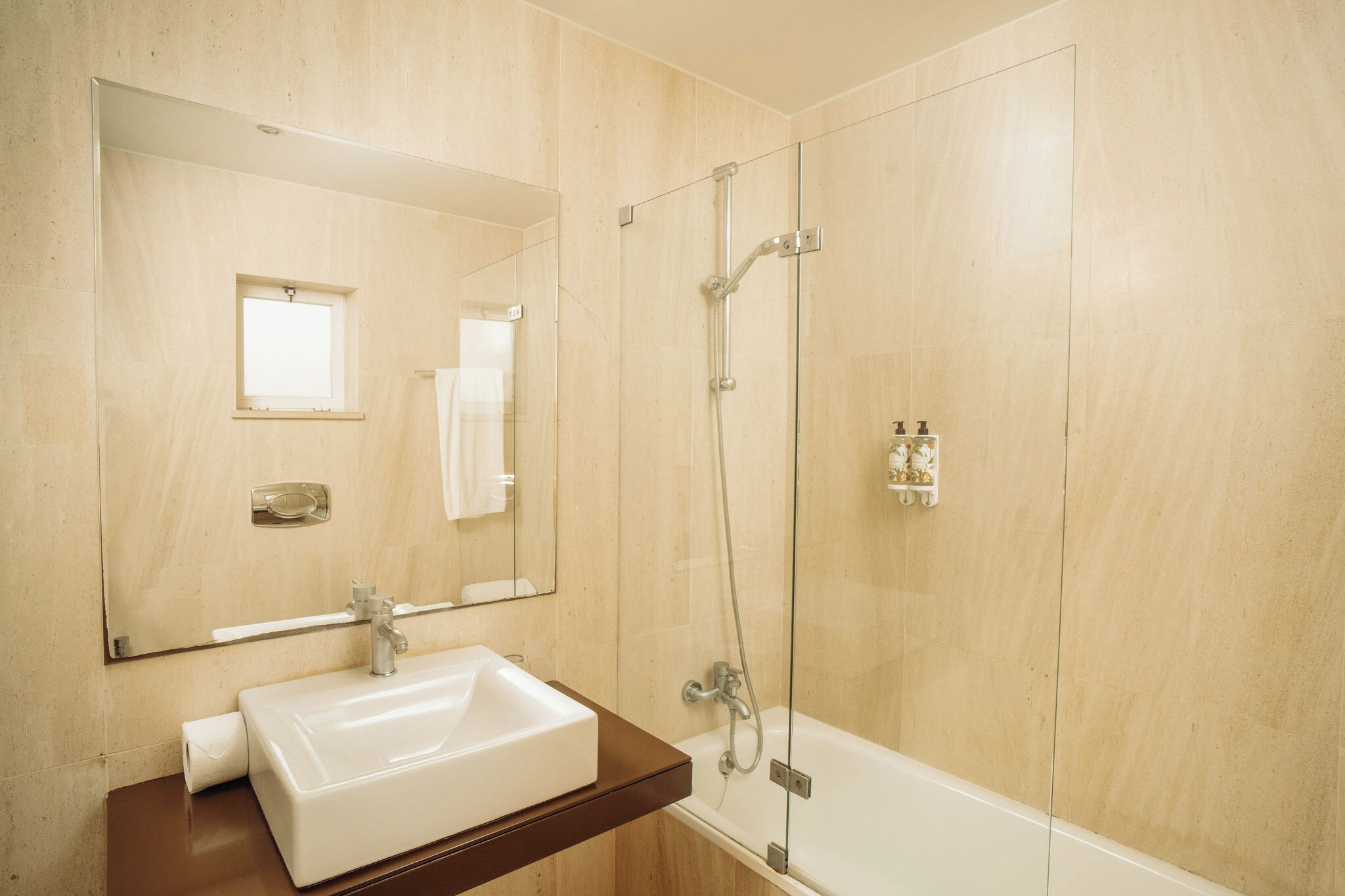 A bathroom with a sink, mirror, shower, and bathtub.