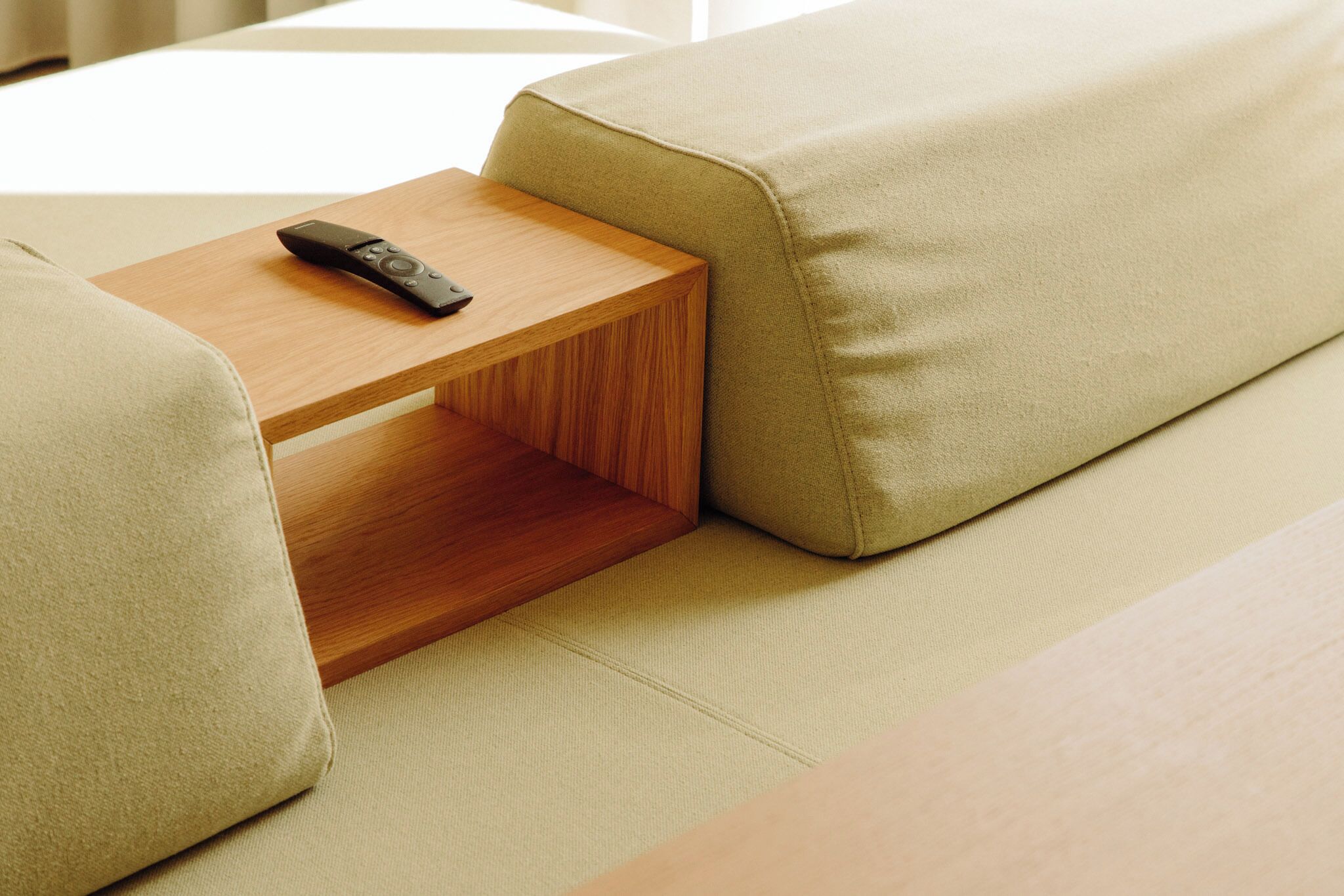 Una habitación moderna con un sofá, una mesita de madera y un control remoto encima.