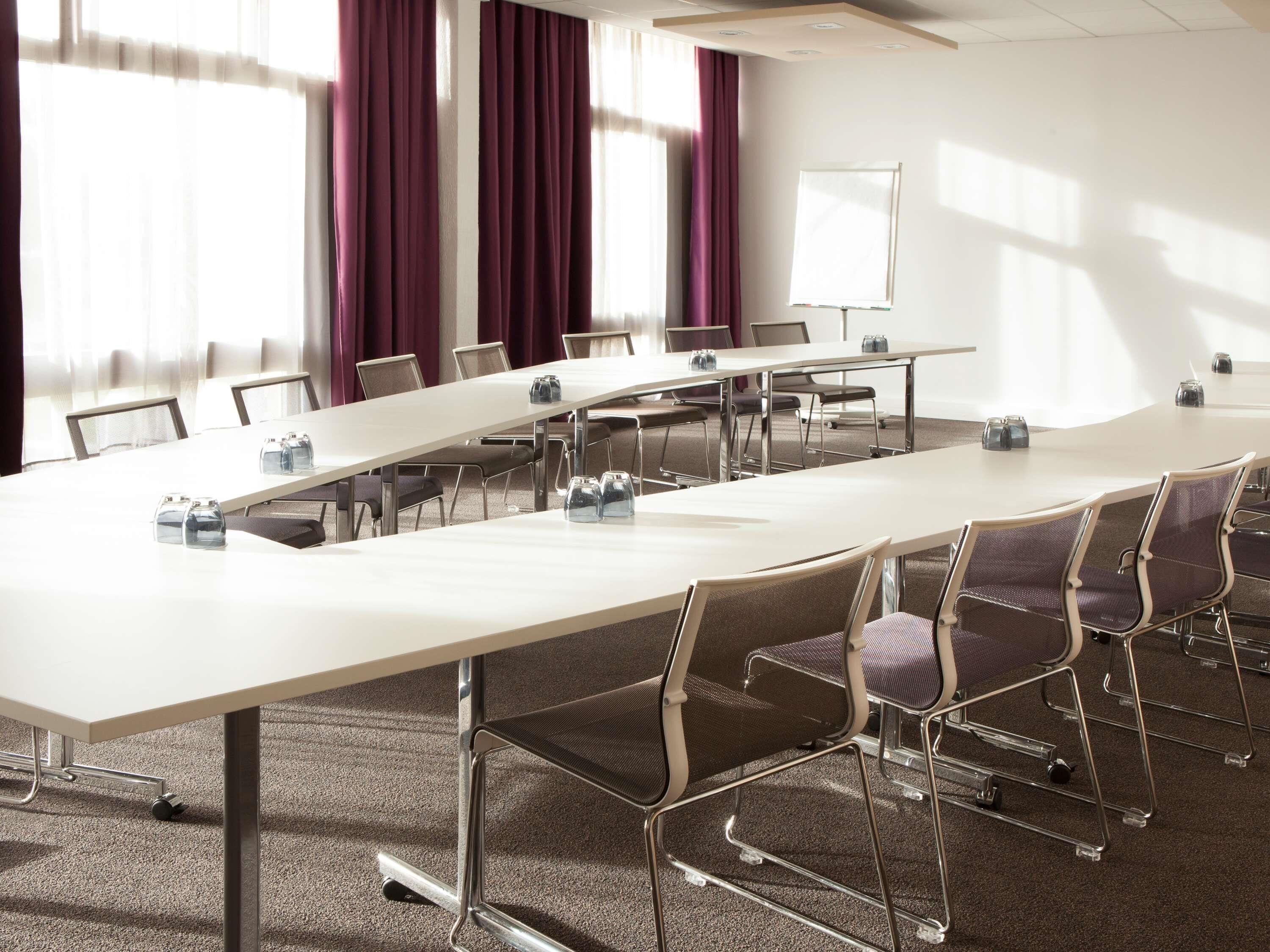 A conference room with a long table, chairs, and a whiteboard.