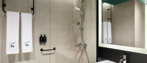 A modern bathroom with a shower, a sink, and two towels hanging on hooks.