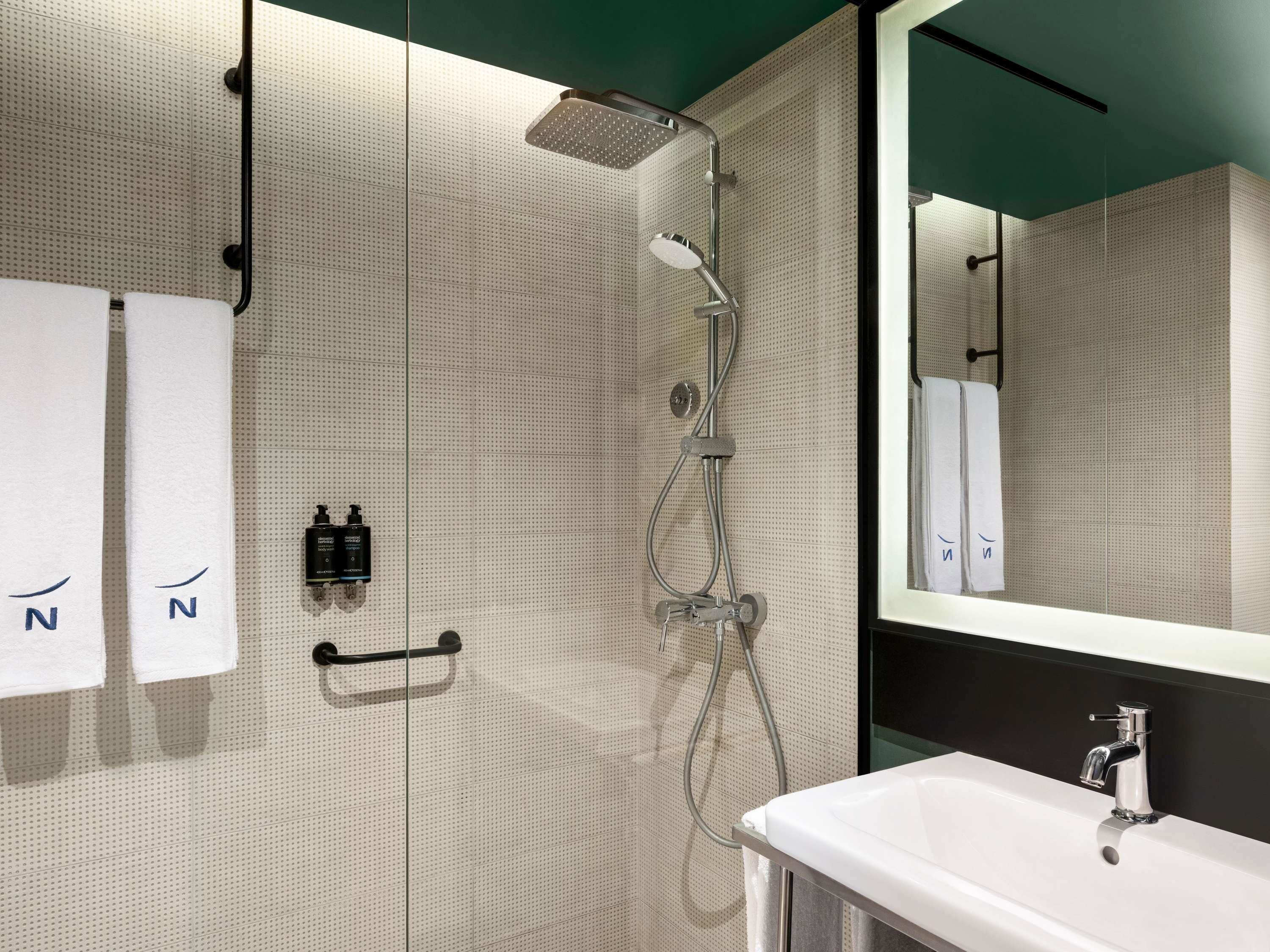 Ein modernes Badezimmer mit Dusche, Waschbecken und Spiegel.