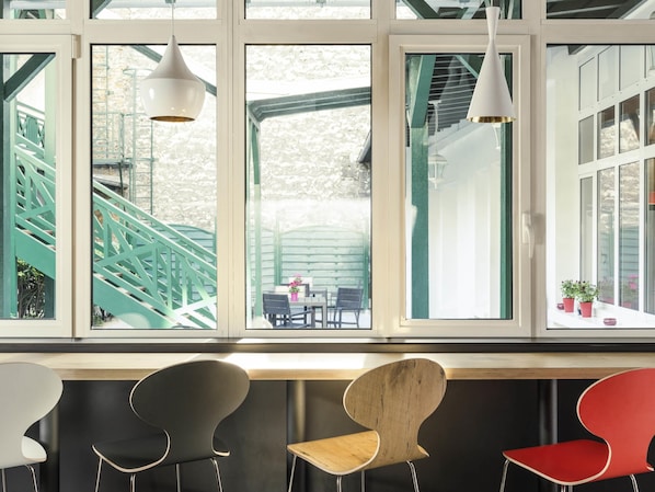 Un interior moderno con ventanas amplias, una escalera y tres sillas.