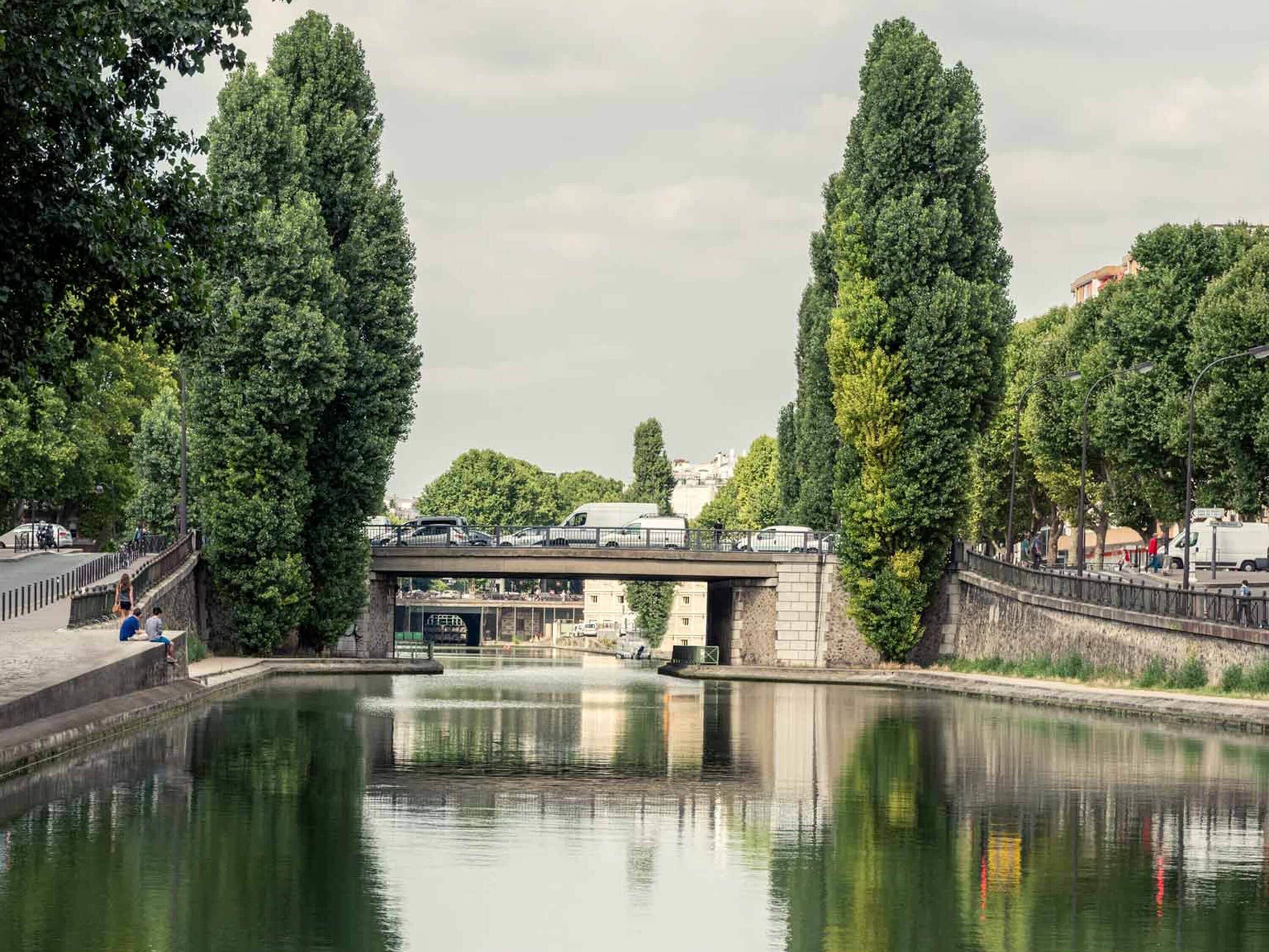 Un canale con un ponte, alberi e una superficie d'acqua calma.