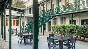 A courtyard with outdoor seating, a green staircase, and a white building with numbered doors. - ibis Paris Levallois Perret (Levallois-Perret)