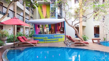 Relax by the pool surrounded by lush greenery and a wooden deck.