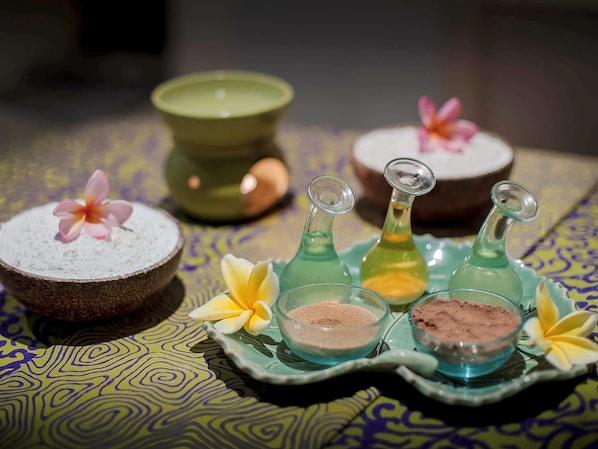 A table with various containers of powders and a green bowl, possibly for a spa or wellness setting.