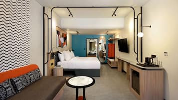 Une chambre d’hôtel moderne équipée d’un lit, d’un coin salon et d’une kitchenette.