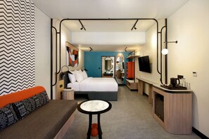 Una habitación de hotel moderna con cama, zona de estar y kitchenette.