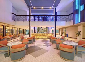 A hotel lobby with a bar area, seating arrangements, and a check-in desk. - TRIBE Bali Legian (Legian)