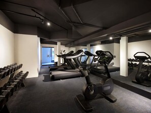 Un gimnasio con cintas de correr, pesas y un espejo grande.