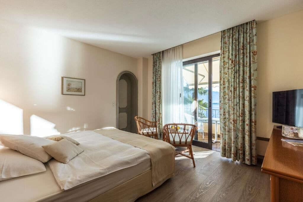 A hotel room with a bed, a television, a chair, and a view of the outdoors.