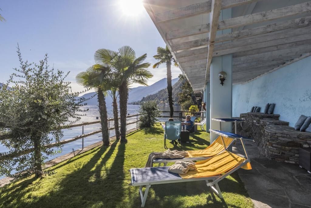 Ein sonniger Außenbereich mit Pool, Liegestühlen und einer Sitzecke aus Stein.