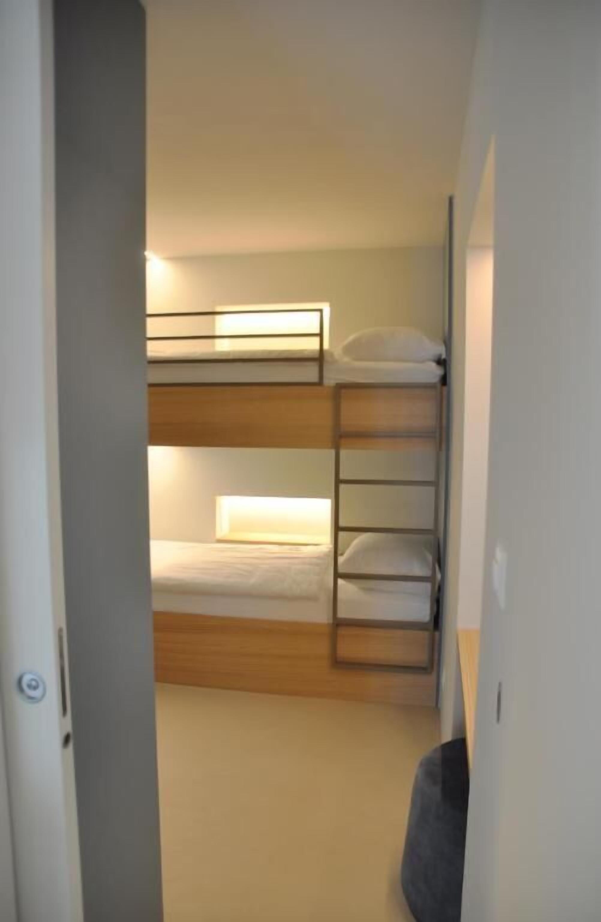 Dormitorio con literas, cabecera de madera y mesita de noche.