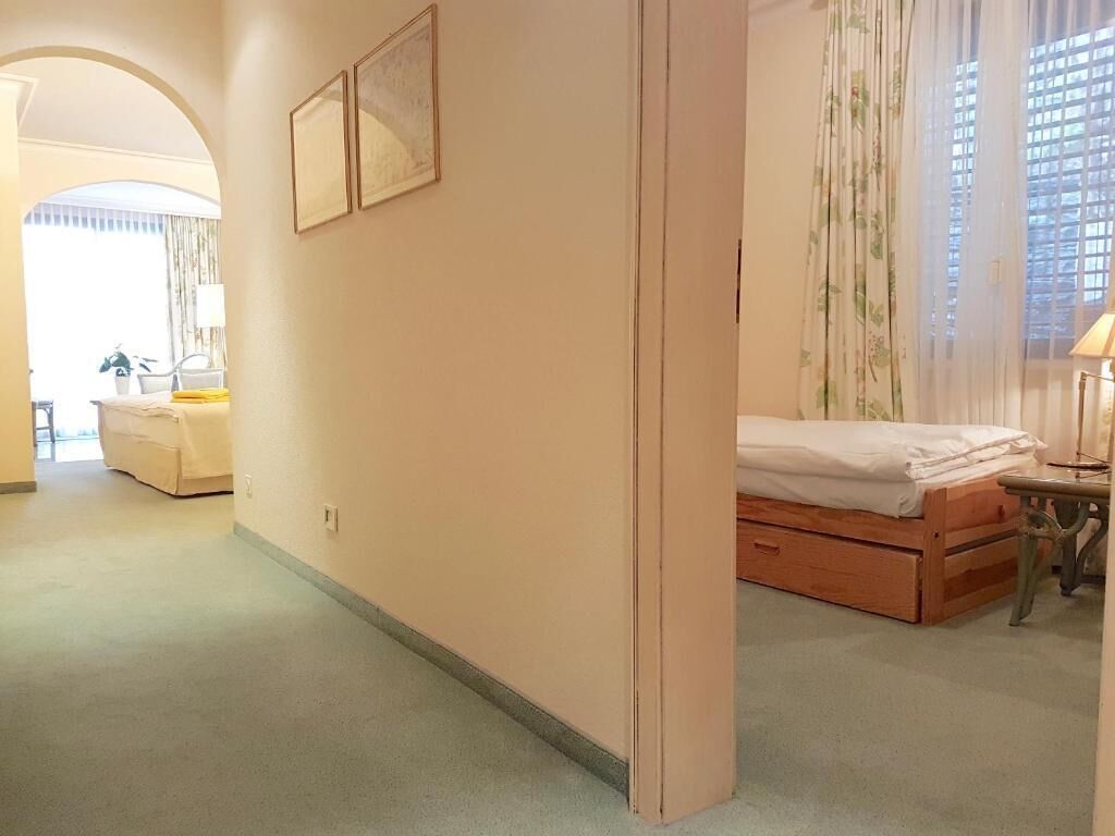 Une chambre d’hôtel avec un lit, un bureau et une chaise. Il y a une fenêtre avec des rideaux et une vue sur l’extérieur.