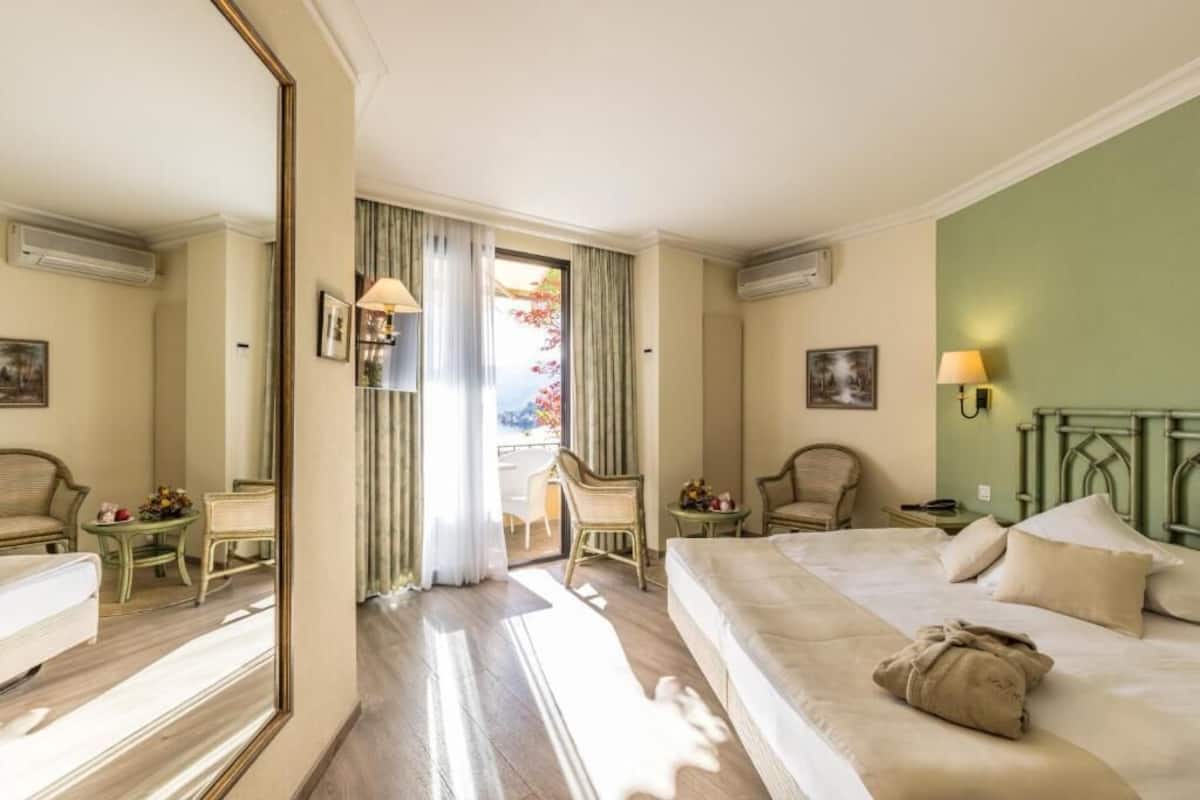 A hotel room with a bed, two chairs, a table, and a mirror.