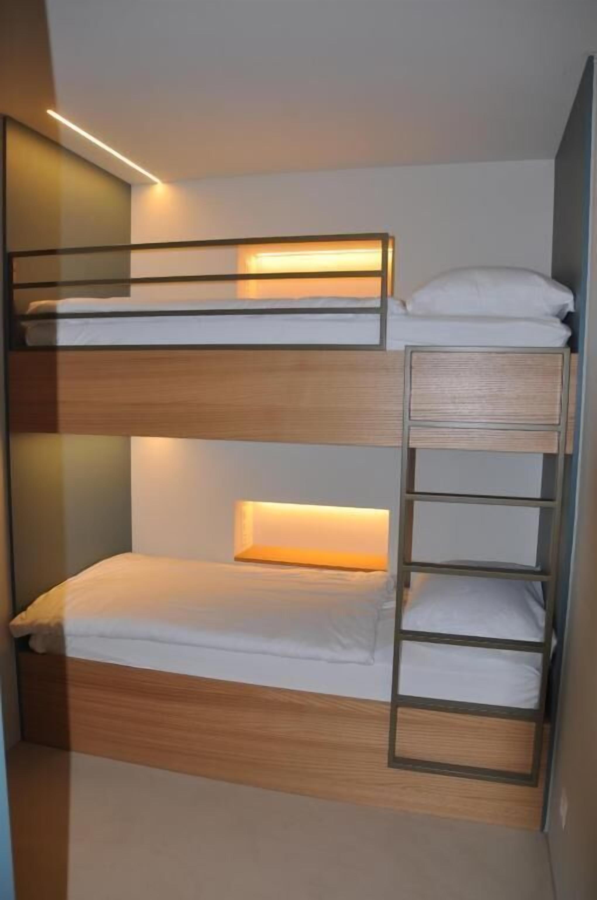 Una cama litera con estructura de madera y cabecera con iluminación integrada.