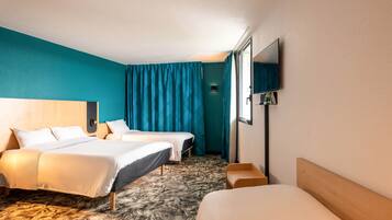 Een hotelkamer met twee bedden, een flatscreen televisie, een houten hoofdbord en een wand in teal blauw.