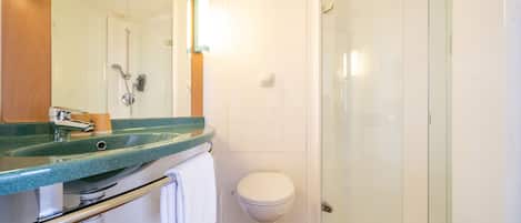 A modern bathroom with a glass shower enclosure, a white toilet, and a granite countertop sink.