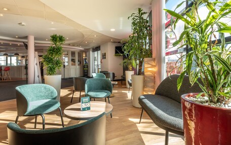 A modern lobby with seating areas, large windows, and indoor plants.