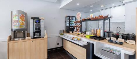 Una cocina moderna con cafetera, refrigerador y una encimera con diversos alimentos y utensilios de cocina.
