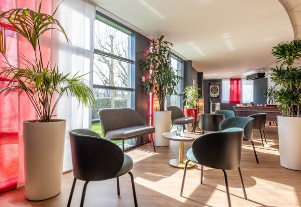 Un espace de détente moderne avec de grandes fenêtres, des sièges confortables et des plantes en pot.