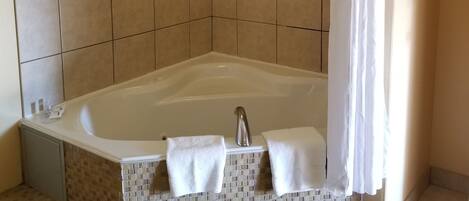 Un baño moderno con una bañera independiente, una cortina de ducha y piso de baldosas.