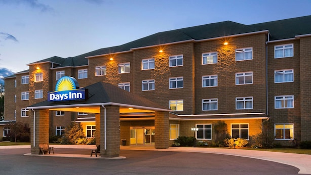A Days Inn hotel with a brick facade, multiple windows, and a covered entrance area. - Days Inn & Conference Centre by Wyndham Oromocto (Oromocto)