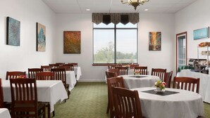 A dining area with round tables, wooden chairs, and artwork on the walls. - Days Inn & Conference Centre by Wyndham Oromocto (Oromocto)