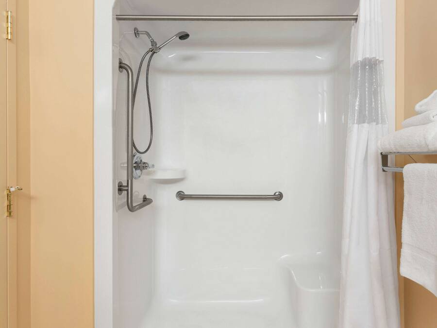 Baño con ducha, barra de apoyo y toallero.