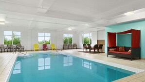 An indoor swimming pool with chairs and a sofa, large windows, and a view of greenery outside. - Days Inn & Conference Centre by Wyndham Oromocto (Oromocto)