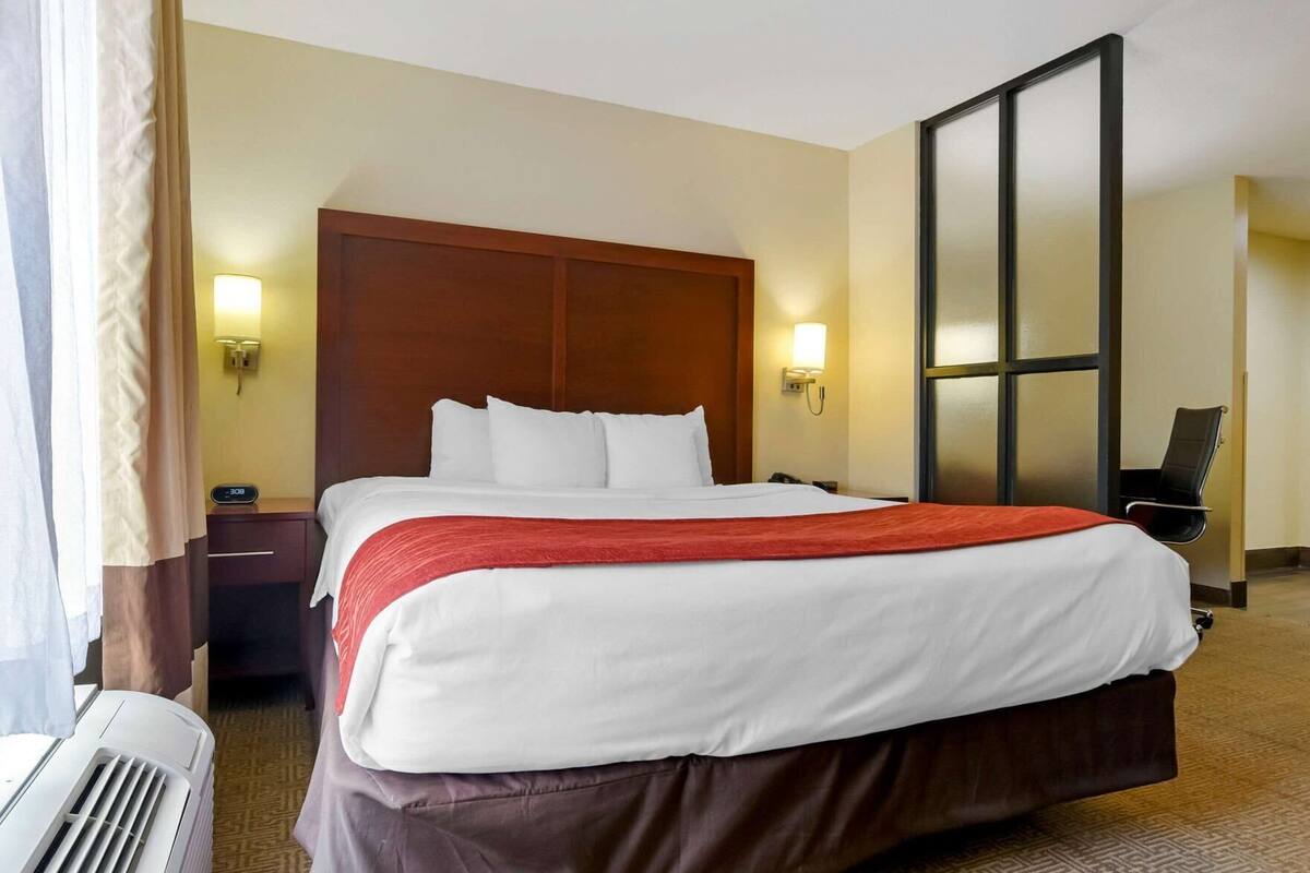 Une chambre d’hôtel avec un grand lit, des tables de chevet, un bureau, une chaise et une fenêtre.