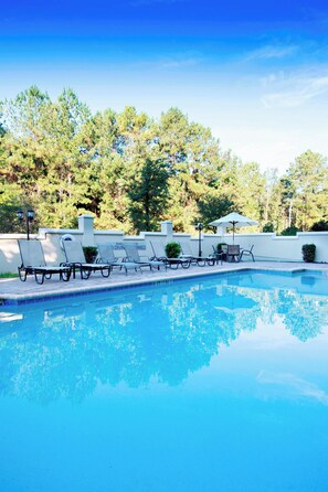 Una piscina al aire libre de temporada, sillones reclinables de piscina