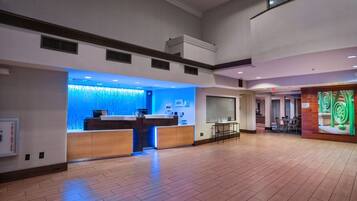 A spacious lobby with a reception desk, a seating area, and a dining section.