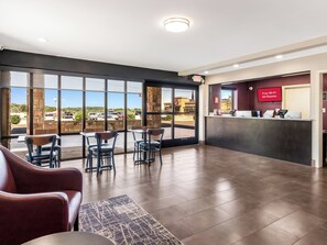 A hotel lobby with a reception desk, seating area, and large windows offering a view of the parking lot. - Red Roof Inn Dandridge (Dandridge)