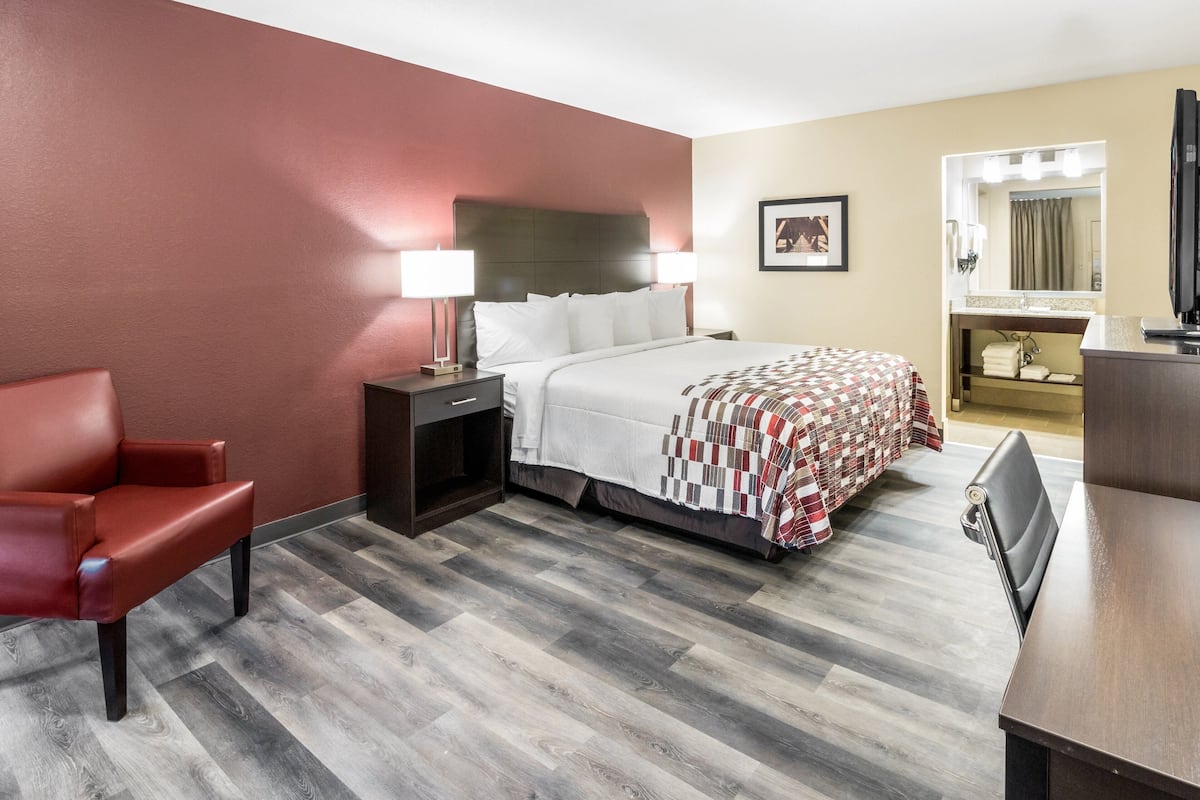 Une chambre d’hôtel comprenant un lit, un bureau, une chaise, une table de chevet et un miroir.